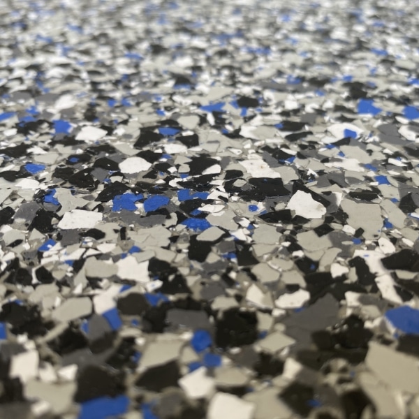 Close-up of a speckled floor with gray, black, and blue flecks. The surface appears textured and shiny, resembling an epoxy finish.