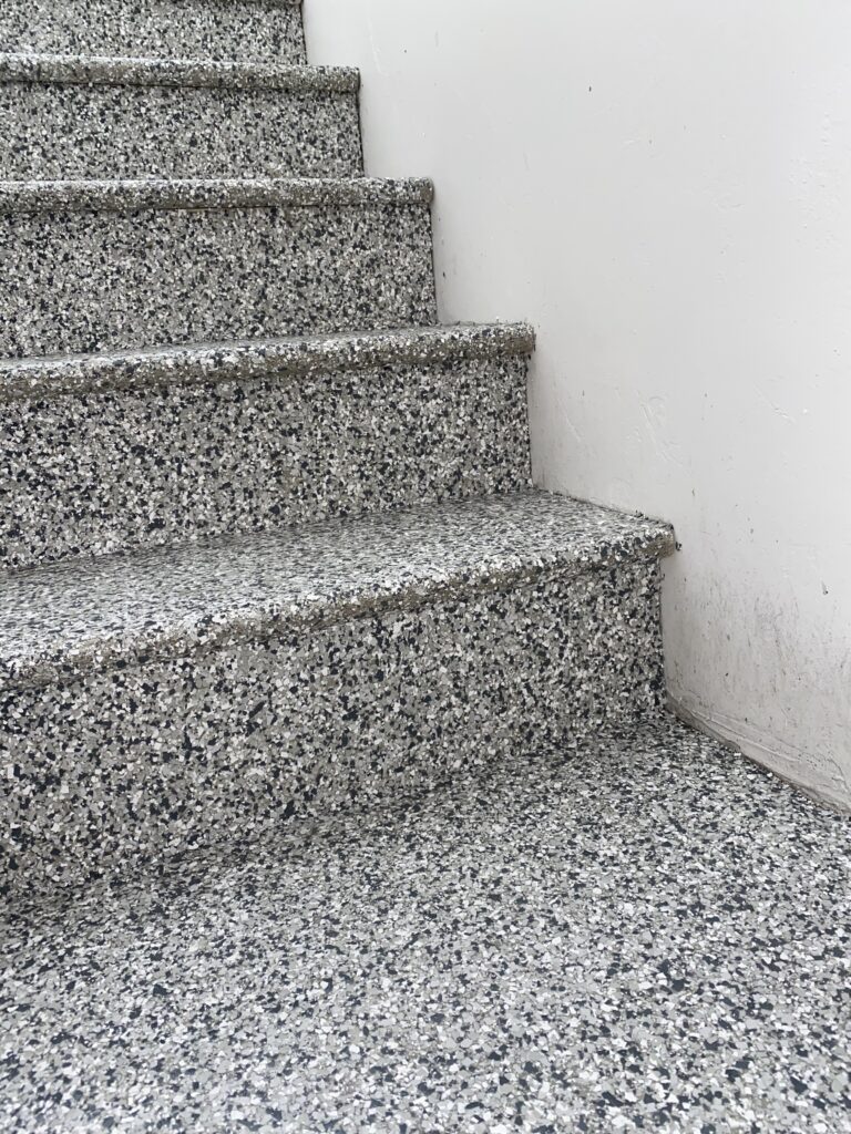 Speckled grey terrazzo staircase with white walls, creating a minimalist and modern interior design. No people or landmarks are visible.