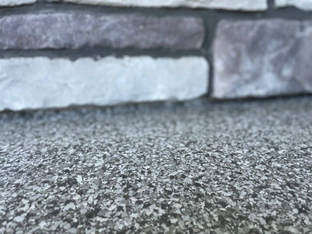 Close-up of a speckled surface and a brick wall background, showcasing texture and color variations in the materials. No people or landmarks present.