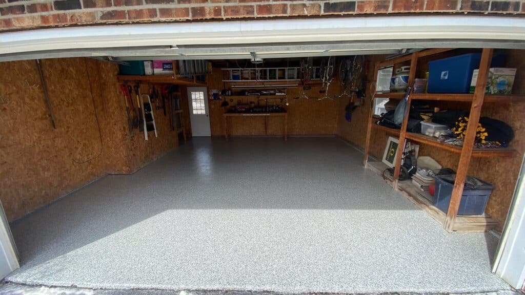 A clean, organized garage with a workbench, shelves holding storage bins and tools, bicycles hanging on the wall, and a closed door.